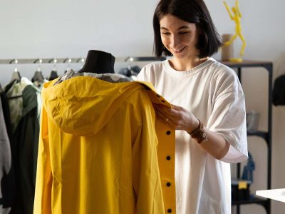 Sewer work with mannequin make adjustments to trendy cloak or raincoat on dummy. Female tailor in tailoring studio create trend clothes. Young designer in professional workshop. Atelier owner business